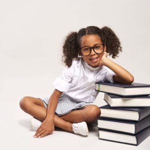 African girl sitting next to stack of books African girl sitting next to stack of books